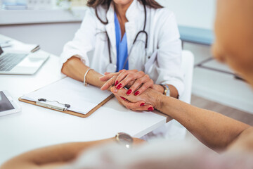 Shot of an doctor holding hands with her patient during a consultation.  Doctor holding hands of female patient at meeting as women health medical care concept.
