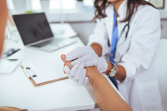 Closeup shot of a nurse holding a patient's hand in comfort. Close-up of home caregiver and senior woman holding hands.  Female patient listening to doctor in medical office. 