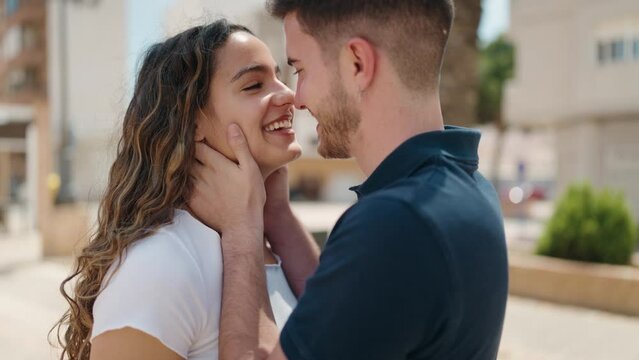 Young hispanic couple smiling confident hugging each other and dancing at park