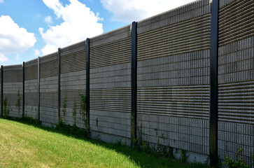 soundproof wall made of concrete porous ribbed material. fence of brown blocks inserted into metal beams, on the street. noise from road traffic does not get into the garden and residential area.
