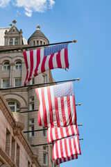 US flags on the old post office building in Washington, D.C., USA. US American flags with stars and stripes in the sunlight.
