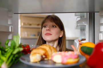 Girl looking inside fridge of ull of different food