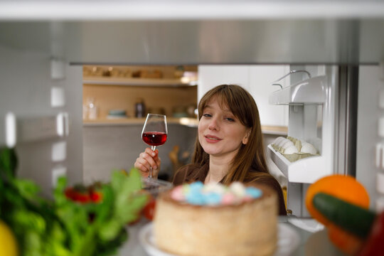 Drunk Woman With A Glass Of Red Wine Chooses Food In The Fridge