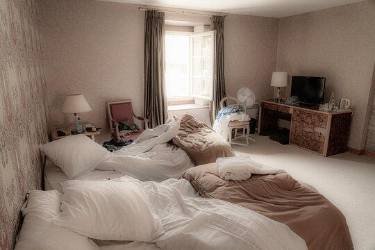 benutzes Hotelzimmer mit unaufger&auml;umten Betten und Fenster