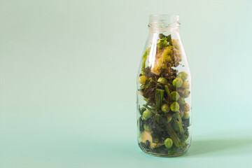 Frozen green vegetables broccoli cabbage peas romanesco cabbage spinach with ice crystals in a transparent bottle close-up.