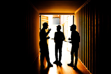 silhouette three workers are meeting in the container yard. silhouette Group of staff engineer standing and checking the containers box at cargo ship yard for export and import.
