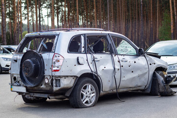 Obraz na płótnie Canvas Shot, damaged cars during the war in Ukraine. The vehicle of civilians affected by the hands of the Russian military. Shrapnel and bullet holes in the body of the car. War of Russia against Ukraine.
