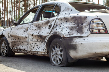 Shot, damaged cars during the war in Ukraine. The vehicle of civilians affected by the hands of the Russian military. Shrapnel and bullet holes in the body of the car. War of Russia against Ukraine.