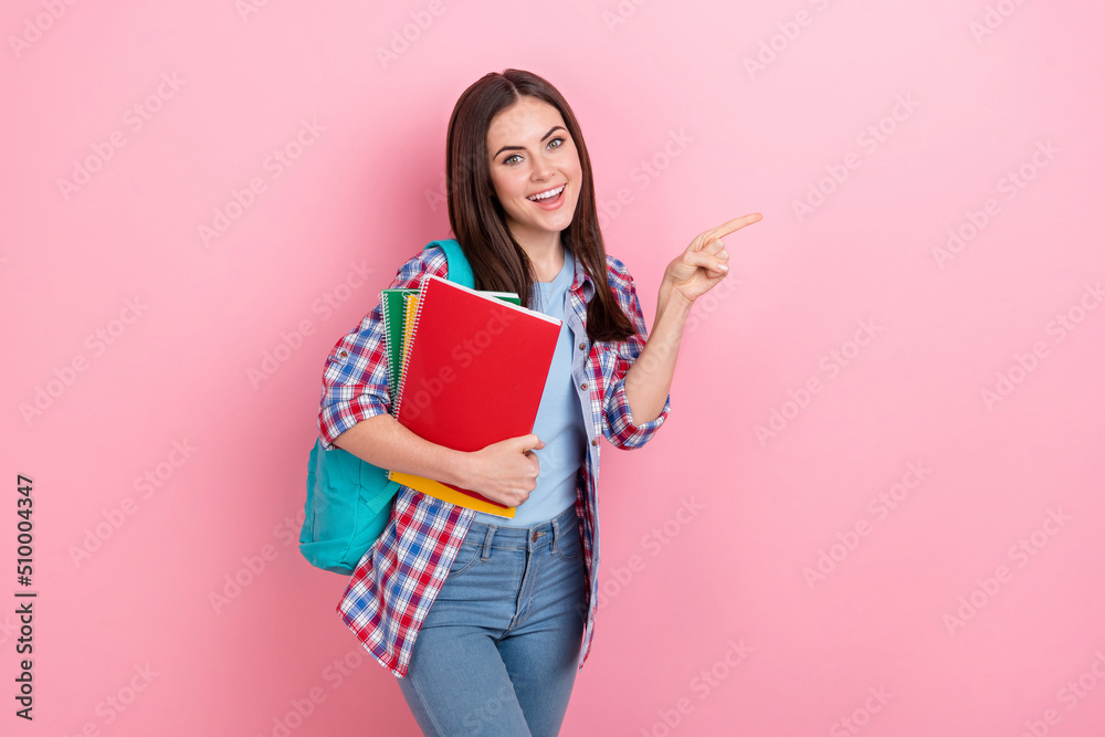 Poster Photo of smiling pretty girl studying in college point finger empty space promote courses isolated on pink color background