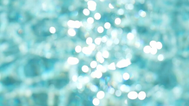 4k stock video footage of blurry  defocused sunny blue water. Abstract blue liquid background with effect of natural blur bokeh with sun light sparkling on surface. Abstract organic Christmas backdrop