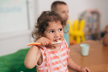 cute young girl brushing her teeth in kindergarden