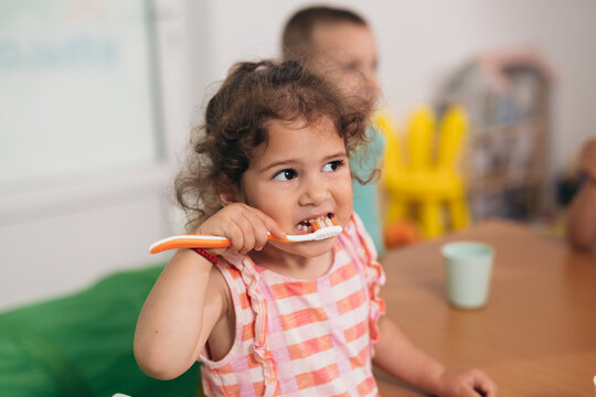 cute young girl brushing her teeth in kindergarden