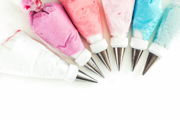 pastry bags with nozzles filled with multicolored glaze on the white background