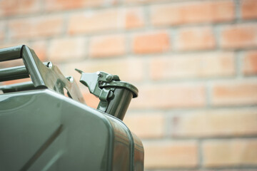 Green Jerrycan against red brick wall. Gas canister full of gasoline. Fuel shortage while...