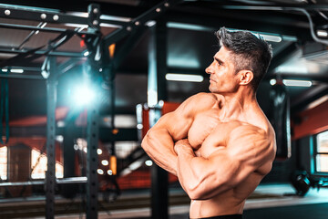 Fototapeta na wymiar Muscular athletic bodybuilder fitness model posing after exercises in gym.