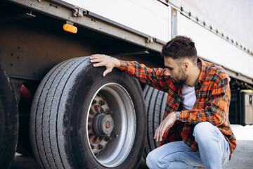 Obraz na płótnie Canvas Man trucker checking wheels on his truck