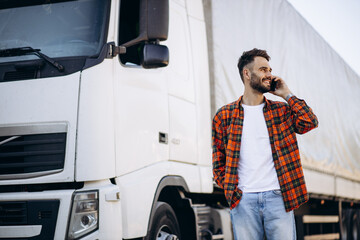 Man trucker talking on the phone by his white truck