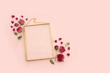 top view of dry rose flower and gold elegant empty frame over pink pastel background. For mock up, copy space