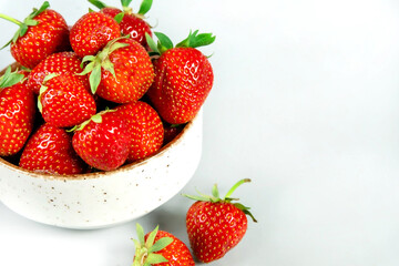 Fresh ripe tasty strawberries in a white bowl on a light background