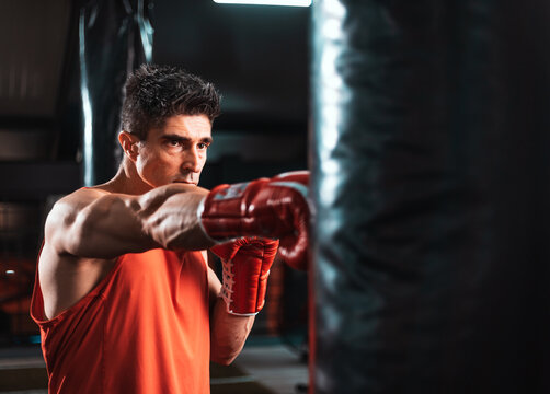 Middle age sportsman boxing workout at gym, guy punching boxing bag, free space