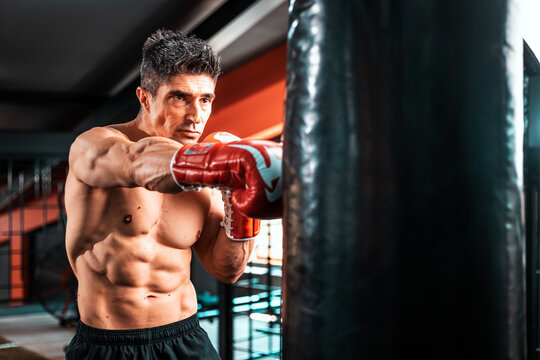 Photo of middle aged strong sports man boxer make exercises in gym and looking aside..