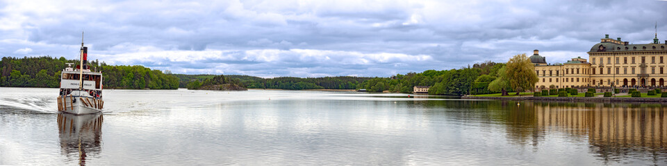 Fototapeta na wymiar panoramic view across the lake Maelaren with the royal palace Drottningholm and the historic ferryboat Prinse Carl Philip from the year 1901 near Stockholm, Sweden