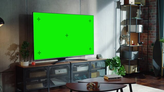 Loft and Cozy Living Room Interior With Television Set with Chroma Key Display, Sofa And Urban City View From The Window. Empty Apartments with Green Screen Placeholder on Monitor
