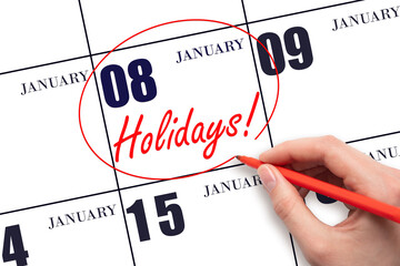 Hand drawing a red circle and writing the text Holidays on the calendar date 8 January. Important date.