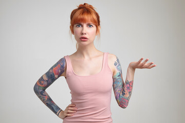 Indoor portrait of young ginger female posing over white wall
