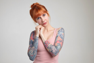 Indoor portrait of young ginger female posing over white wall