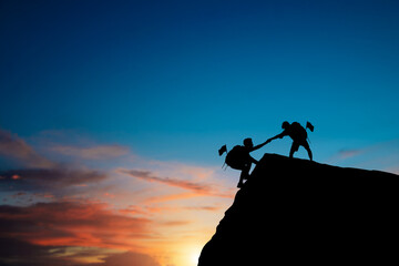 Silhouette of two people helping each other hike up on a mountain at sunrise. Giving a helping hand, and active fit lifestyle concept. Couple hiking help each other. Together they will succeed. - obrazy, fototapety, plakaty