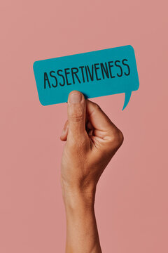 holds a sign with the text assertiveness