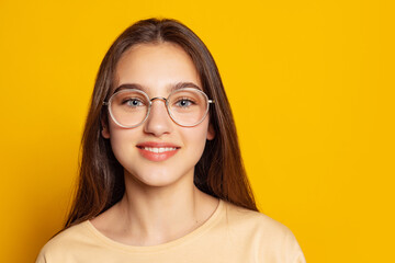 One emotional charming girl in casual style outfit posing isolated on yellow background. Concept of beauty, art, education, youth and emotions