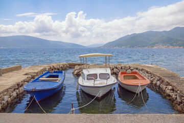 Fototapeta na wymiar Beautiful Mediterranean landscape. Fishing boats at small stone jetty. Montenegro, Adriatic Sea. View of Bay of Kotor, Tivat