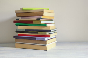 Stack of different colorful books on rustic table. Copy space