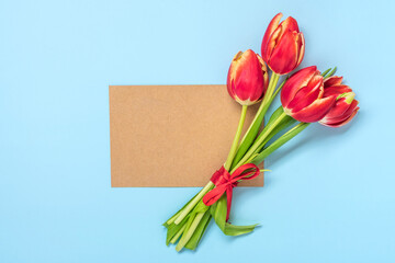 Bouquet of red tulips, card on blue background Top view Flat lay Holiday greeting card Happy moter's day, 8 March, Valentine's day, Easter concept Copy space Mock up