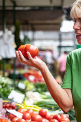 Fototapeta premium Senior blonde woman model holding two organic tomatoes
