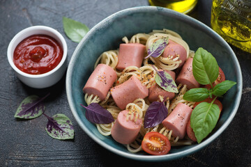 Green bowl with threaded spaghetti hot dog bites on a dark-brown stone background, middle close-up, studio shot