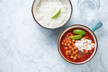 Bowls with indian chana masala or chole masala and basmati rice. Top view on a light-grey marble background, horizontal shot, copy space