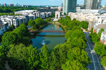 an aerial shot of the silky green waters of the lake with a rust colored metal bridge over the...
