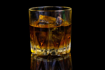 Glass of whiskey with ice on a black background