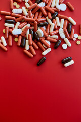 Flat lay different colorful Medical pills on red background,  Vitamin deficiency, avitaminosis concept, assorted pharmaceutical medicine pills, Dietary supplement healthcare product.