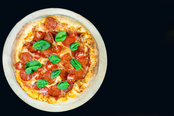 Pepperoni pizza with fresh tomatoes on a dark background, top view