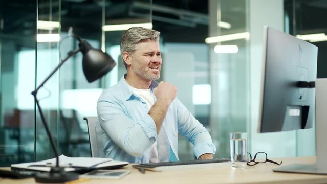 Angry mature business man worker working on computer in office. Upset employee entrepreneur frustrated Looks at the monitor screen. nervous breakdown breaks shouting Stressful sitting at desk