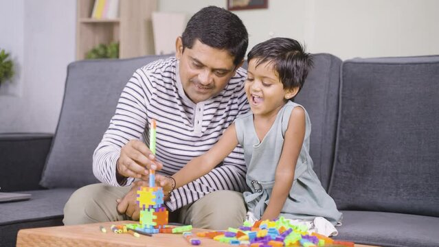 Father and little daughter making toy home otr tower during weekend holiday - concept of spending family time, childhood growth and development