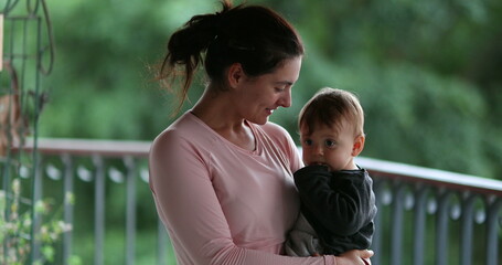 Fototapeta premium Casual mother with infant baby in arms smiling to camera portrait