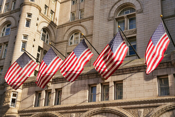 US flags on the old post office building in Washington, D.C., USA. US American flags with stars and stripes in the sunlight.