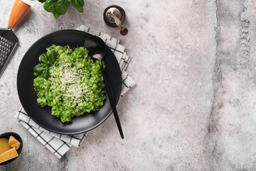 Italian risotto. Delicious risotto in white plate with pesto sauce or wild garlic pesto, basil, parmesan cheese and glass of white wine on old light grey table background. Top view with copy space.