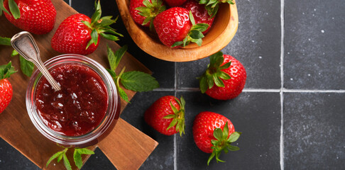Strawberry jam. Strawberry jam in glass jar with fresh berries plate on an old black cracked tile table background, closeup. Homemade strawberry fruity jam. Top view with copy space.