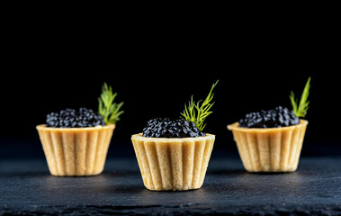 Tartlets with black caviar and dill. Focus on the front tartlet.